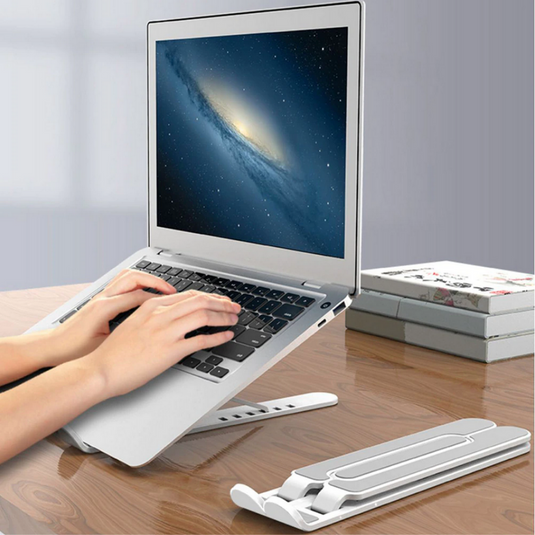 Person using a laptop on a adjustable stand with books in the background