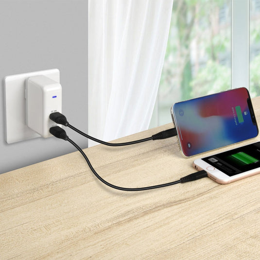 Two USB cables plugged into a wall adapter and plugged into two separate phones showcasing charging capabilities.